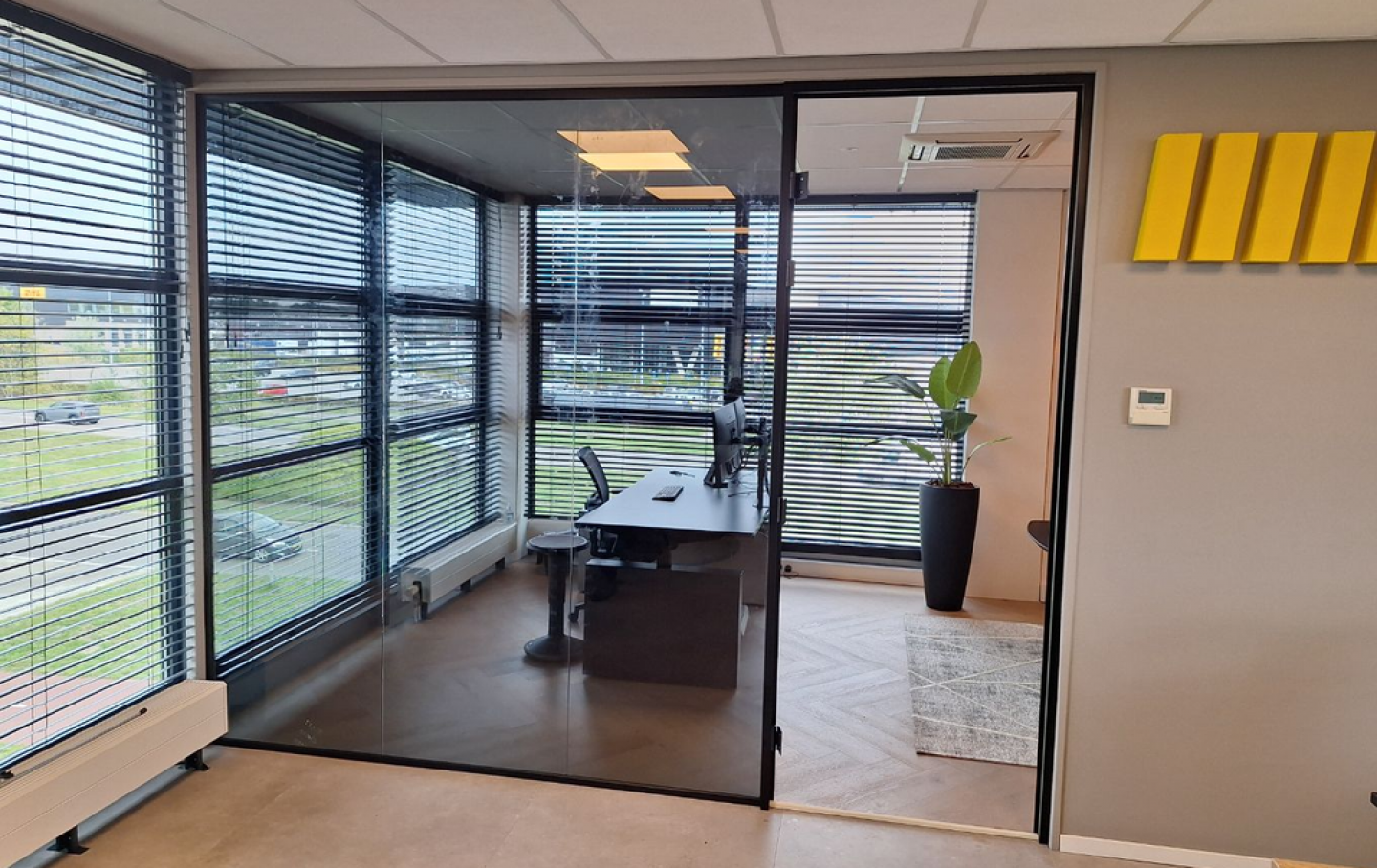 geluidsisolerende glazen wand met aanslagdeur - uitgevoerd in grijs getint glas